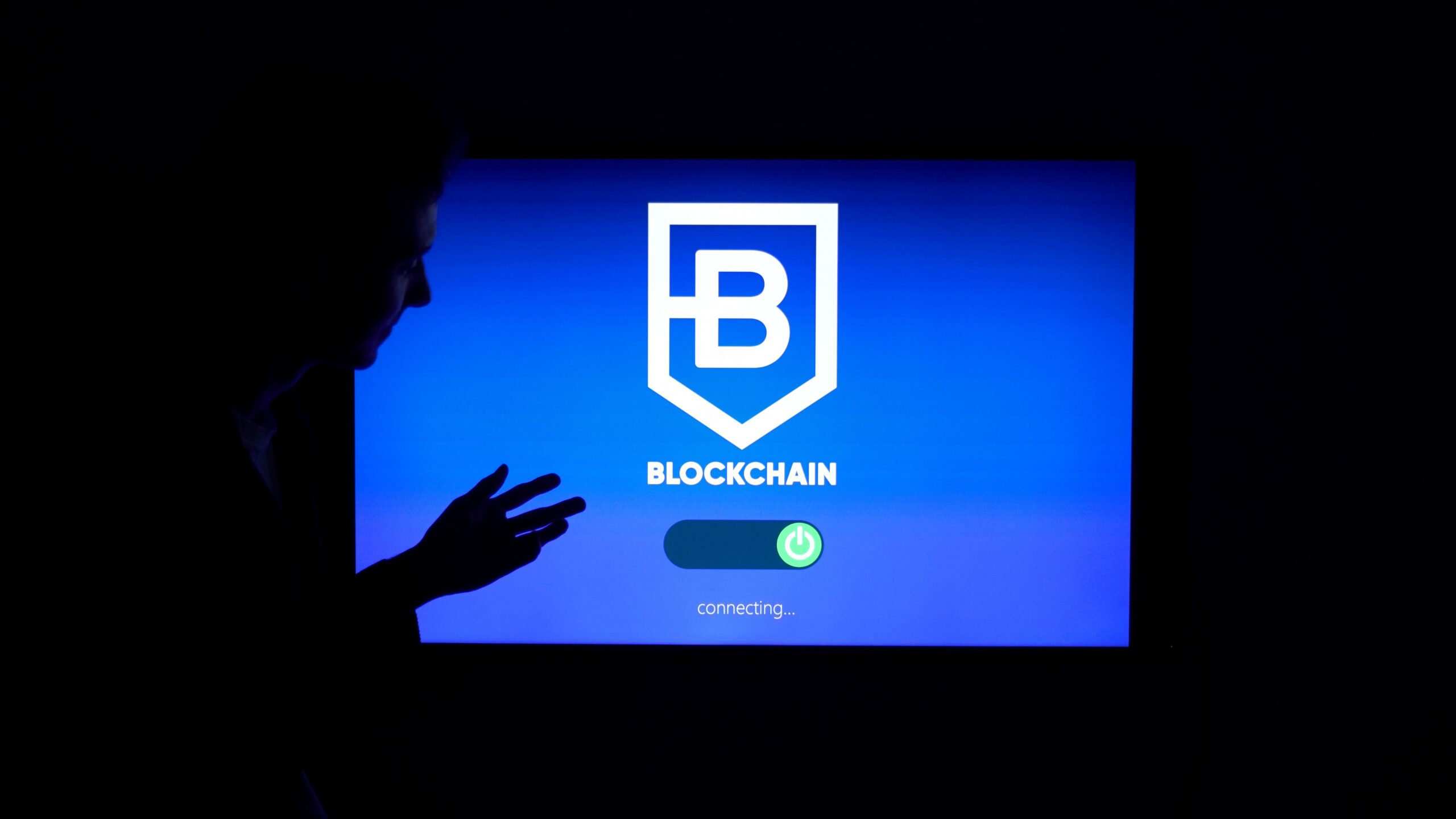 HOME Silhouette of a person interacting with a blockchain technology display screen, showcasing digital innovation.